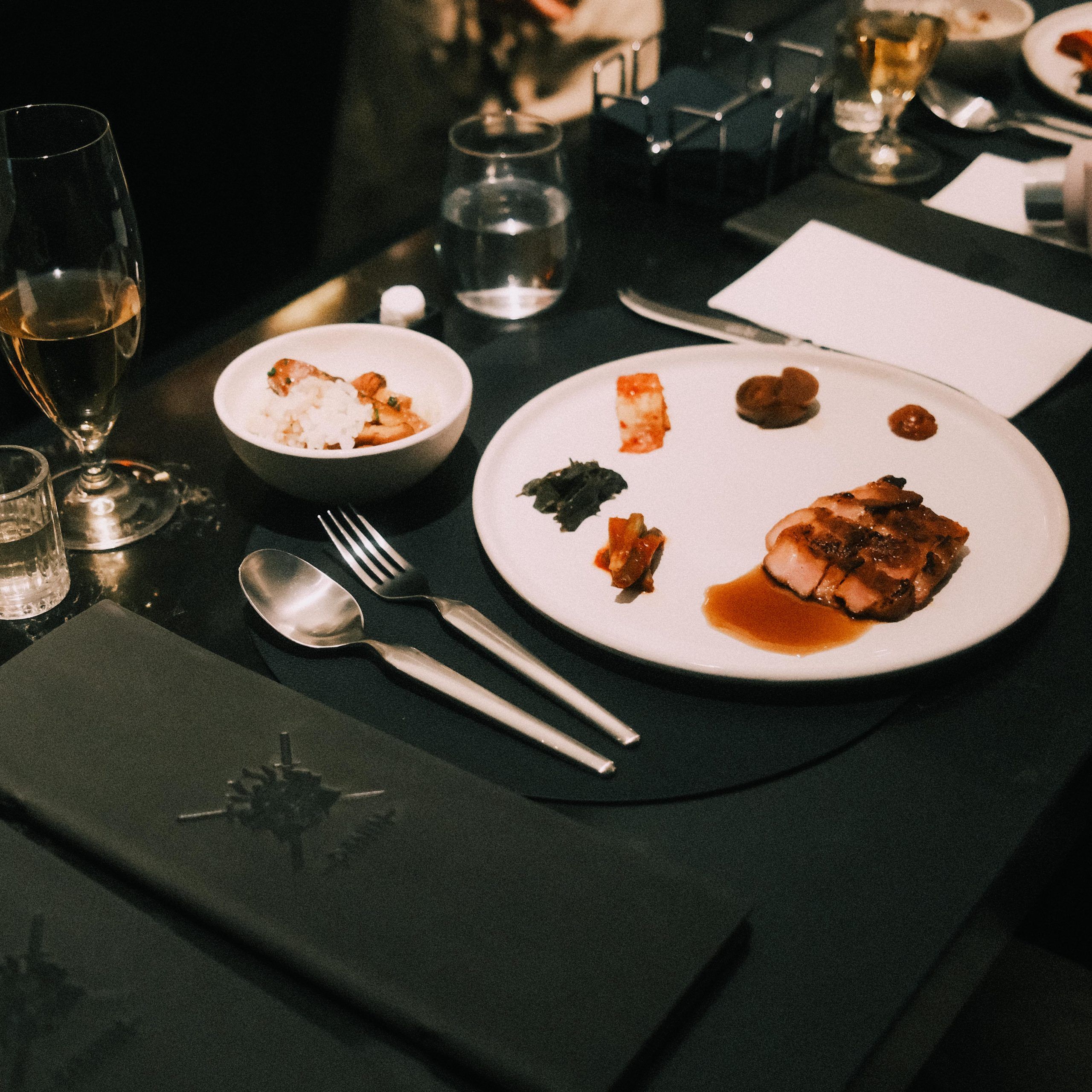A plated main course with sides at a place setting at Ronin Omakase